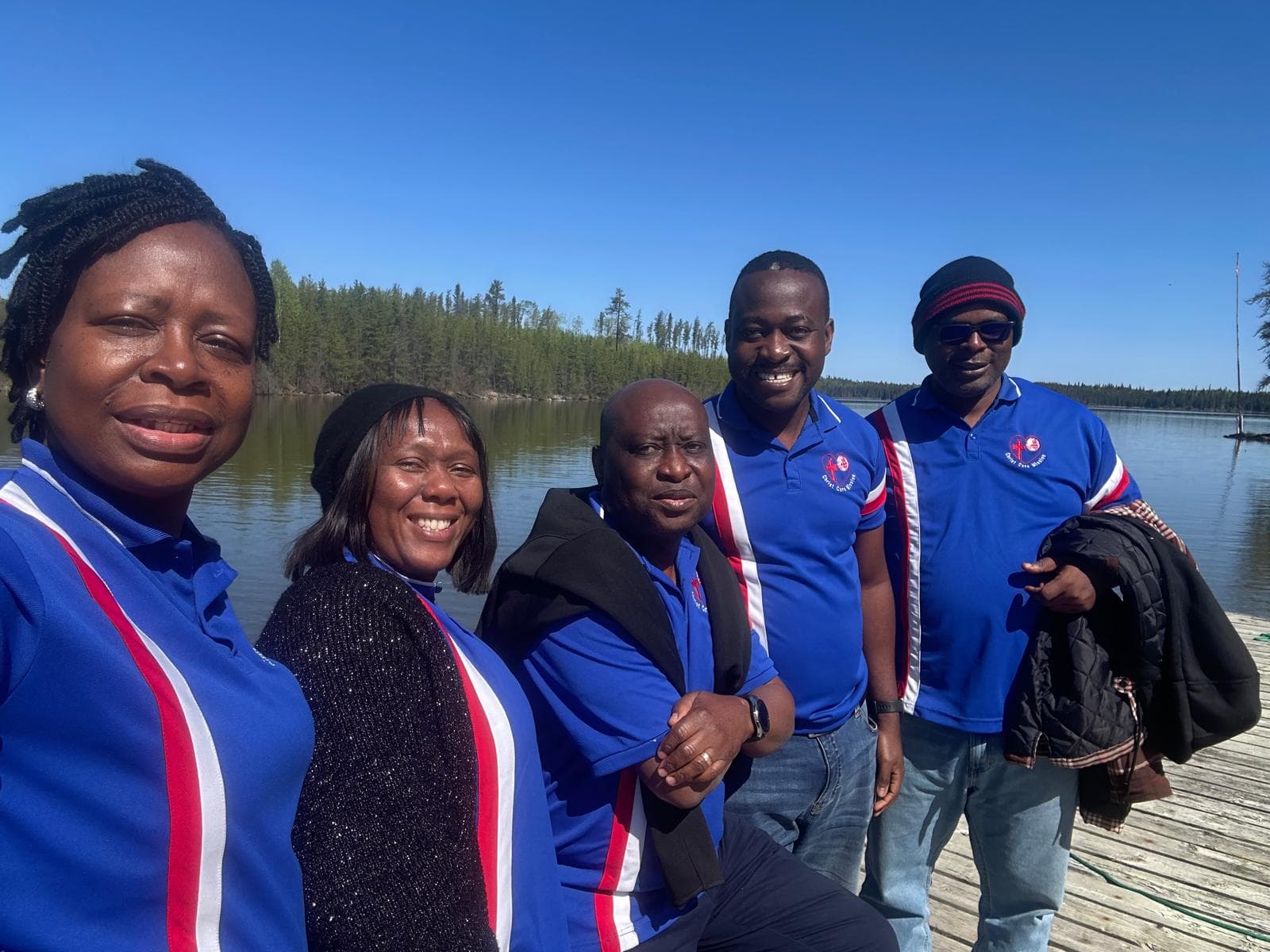 Mission team members in blue shirts beside the water at Sandy Bay in June 2024